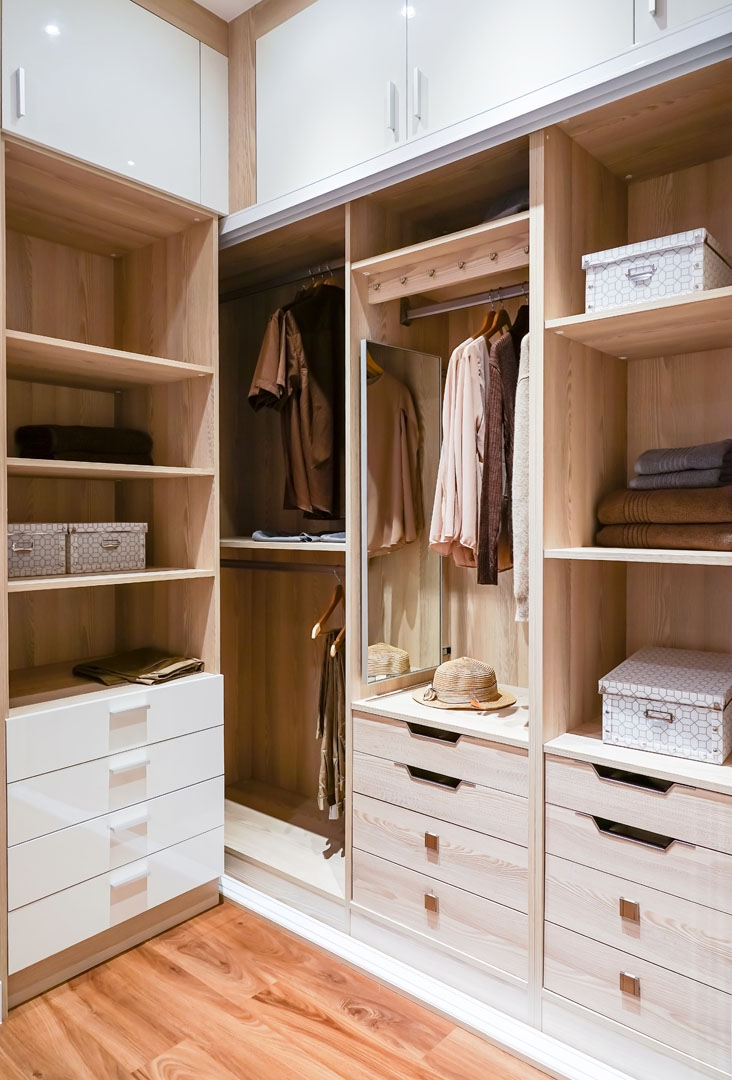 modern wooden wardrobe with clothes hanging on rail in walk in c