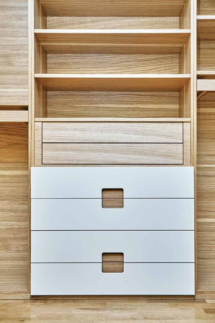 Internal details of wooden wardrobe with finger pull design and light gray cabinet doors